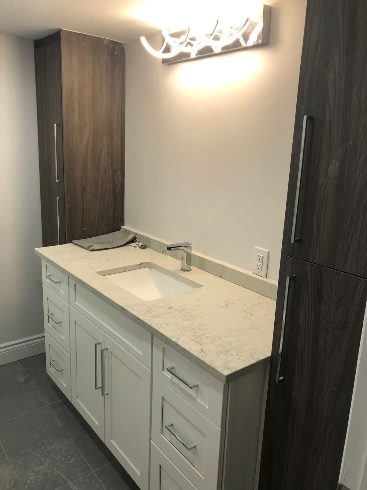 White shaker bathroom vanity with quartz countertop and wood tower cabinets