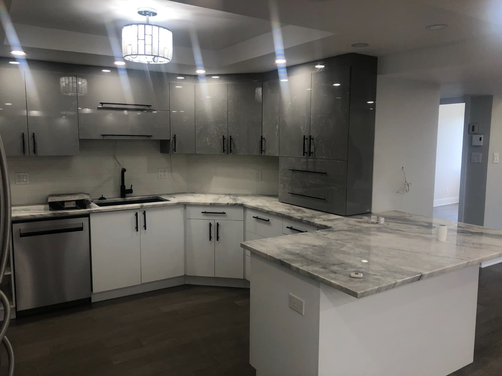 Dark grey gloss L-shape kitchen with swirled grey quartz countertop