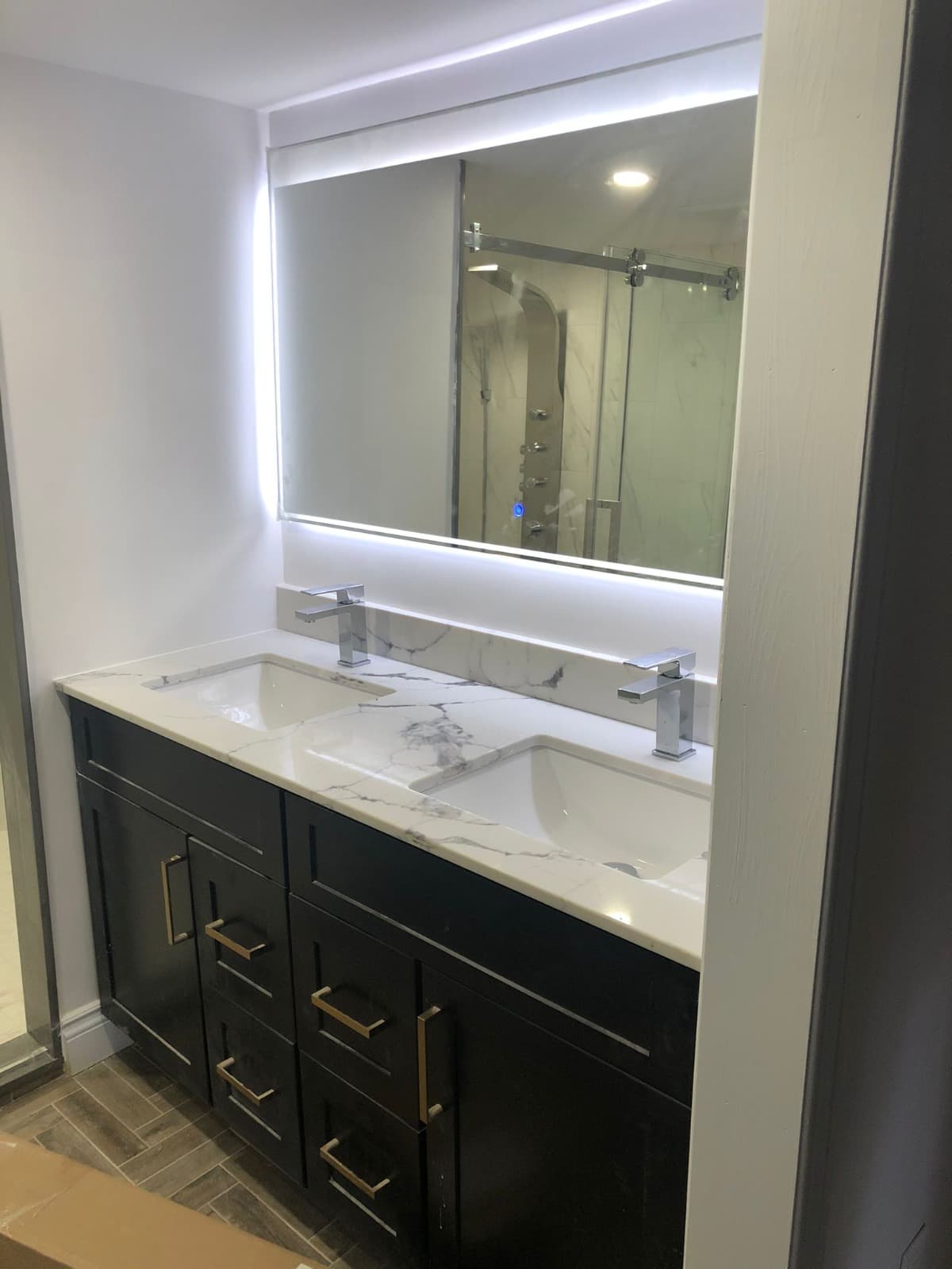 Dark wood double-sink vanity with calacatta countertop and backlit mirror