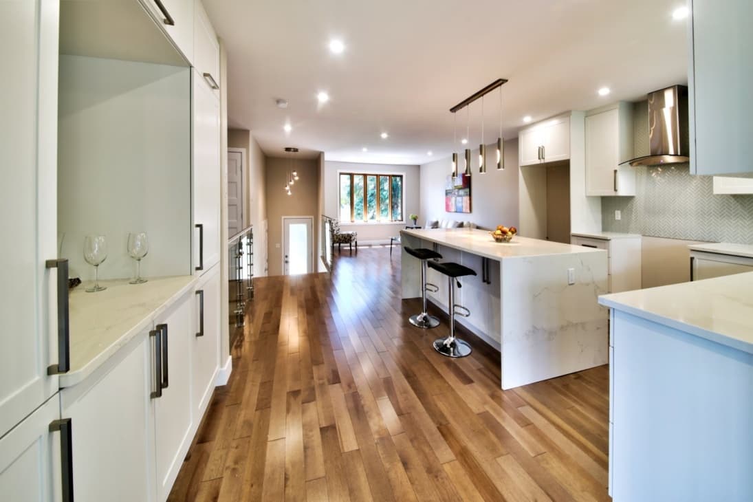 White kitchen with quartz peninsula and herringbone tile backsplash