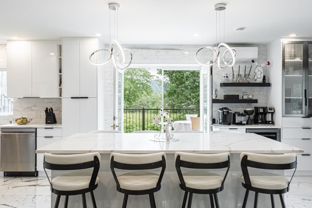 Large all-white kitchen with calacatta quartz island and ring pendants