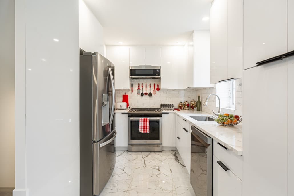 Compact gloss white kitchen with subway tile and marble floor